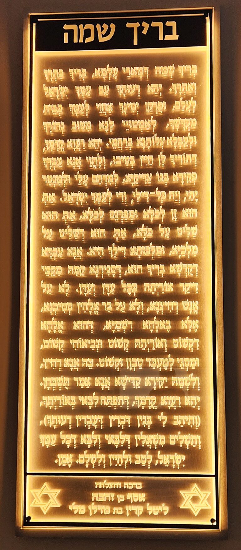 שלט בריך שמיה עם אותיות זהובות ותאורה על קיר