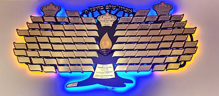 עץ הנצחה רחב עם לוחיות זהובות ותאורה כחולה