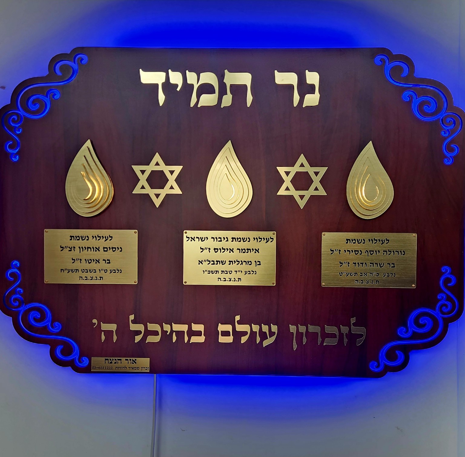 נר תמיד עם שלוש להבות מוזהבות, שני מגני דוד ולוחיות הקדשה, בתאורה כחולה